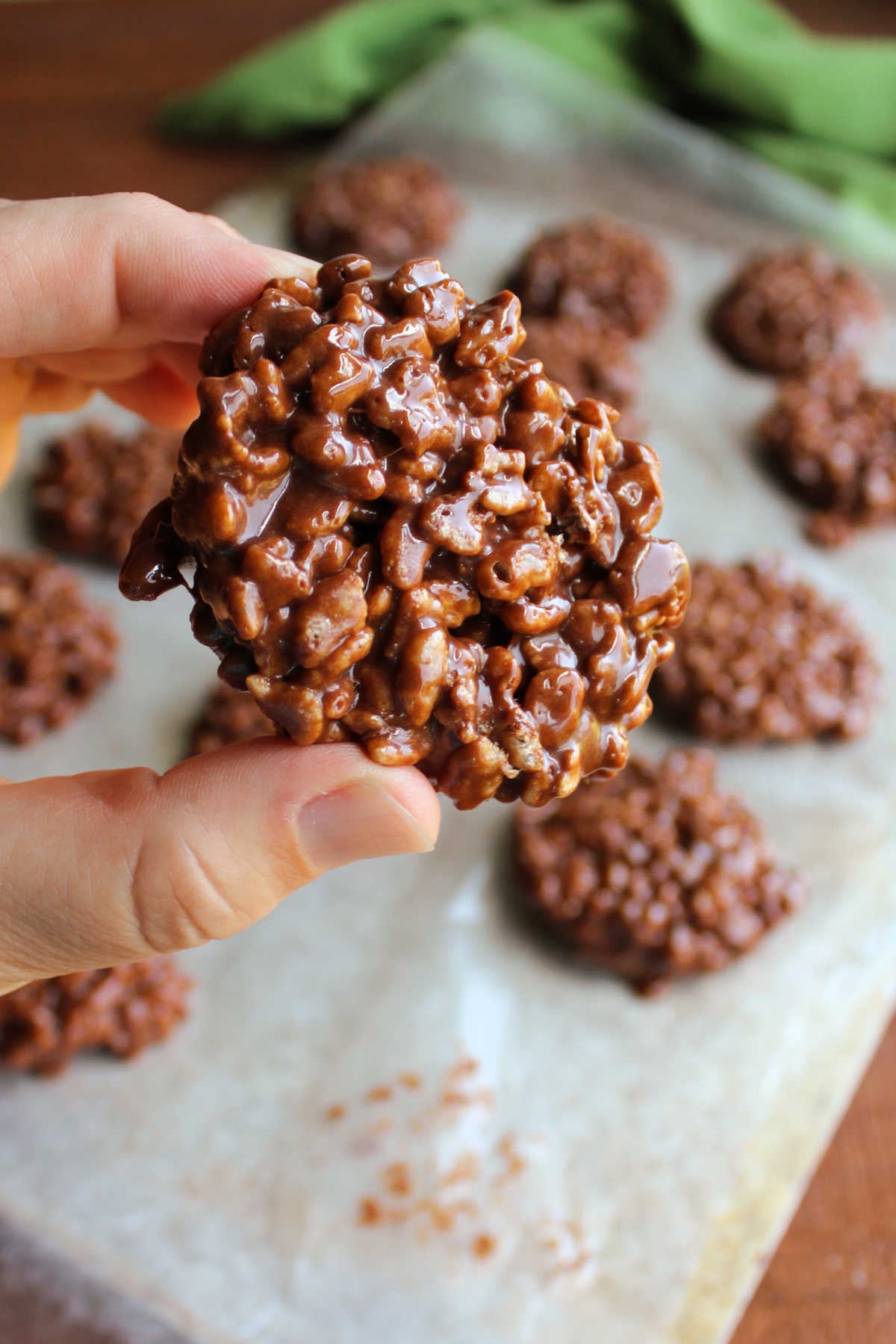 Homemade Star Crunch 9 Hand holding a homemade star crunch with a wax paper lined baking sheet with more no bake cookies in the background.