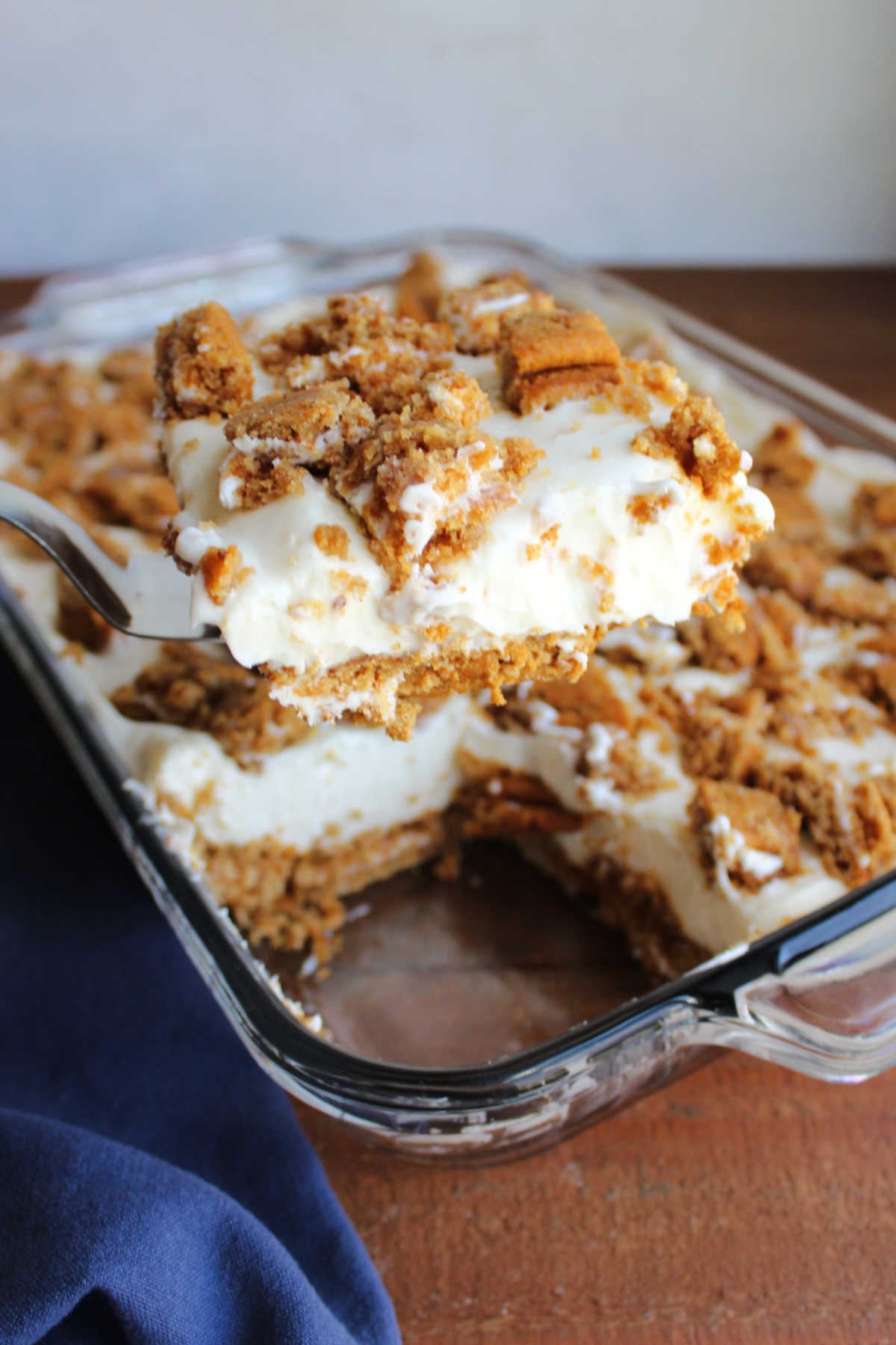 Spatula lifting piece of no bake cheesecake out of the pan showing the oatmeal creme pie crust and bits of cookie on top with a creamy vanilla cheesecake filling in the middle. 