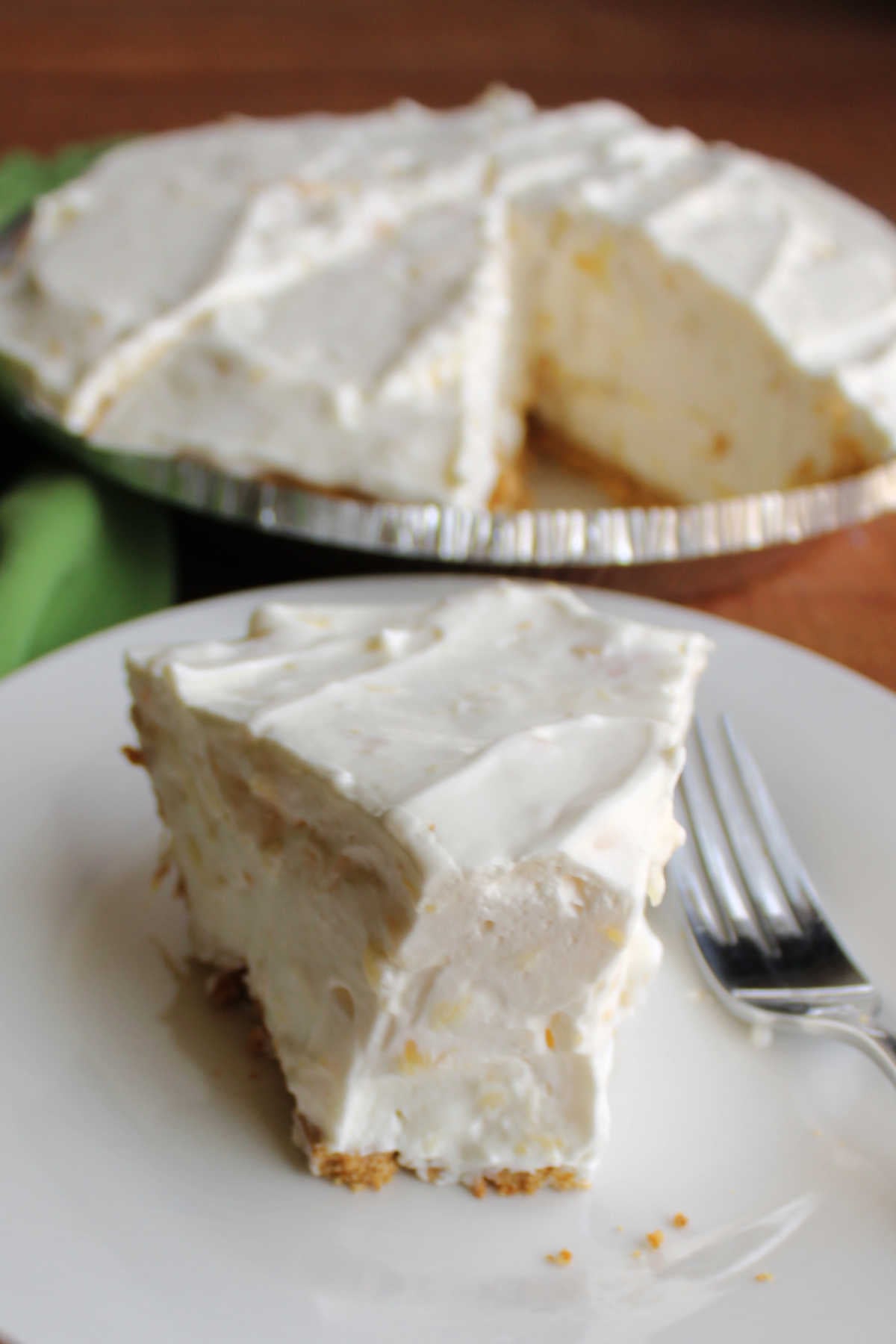 Piece of creamy no bake pineapple pie with the tip missing, showing fluffy creamy filling inside. 