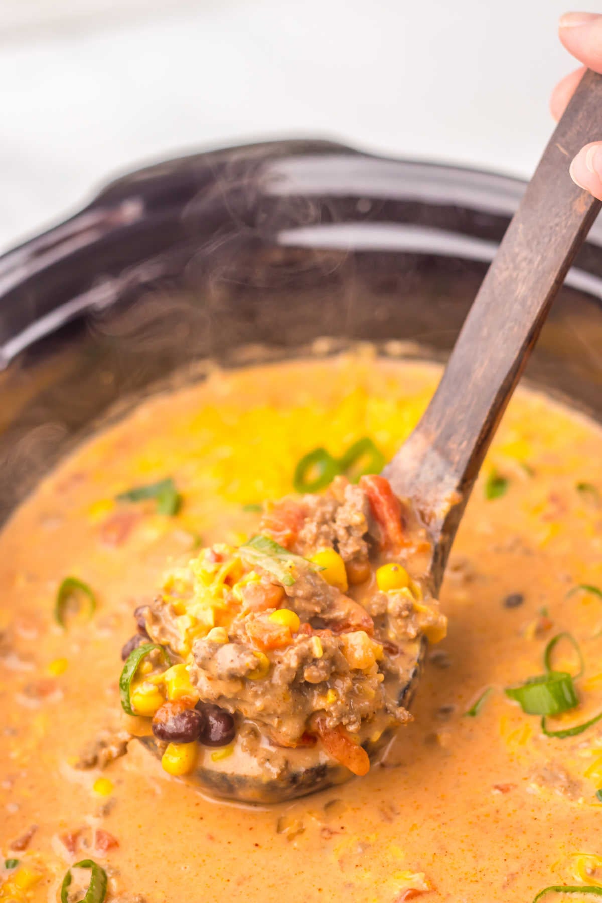 Ladle scooping a serving of creamy taco soup out of a crockpot, ready to serve. 