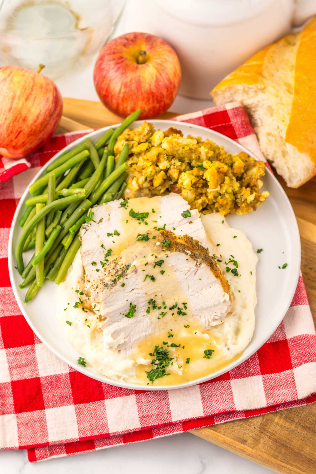 Dinner plate with slow cooked turkey breast served over mashed potatoes with apple cider gravy, green beans, and stuffing.