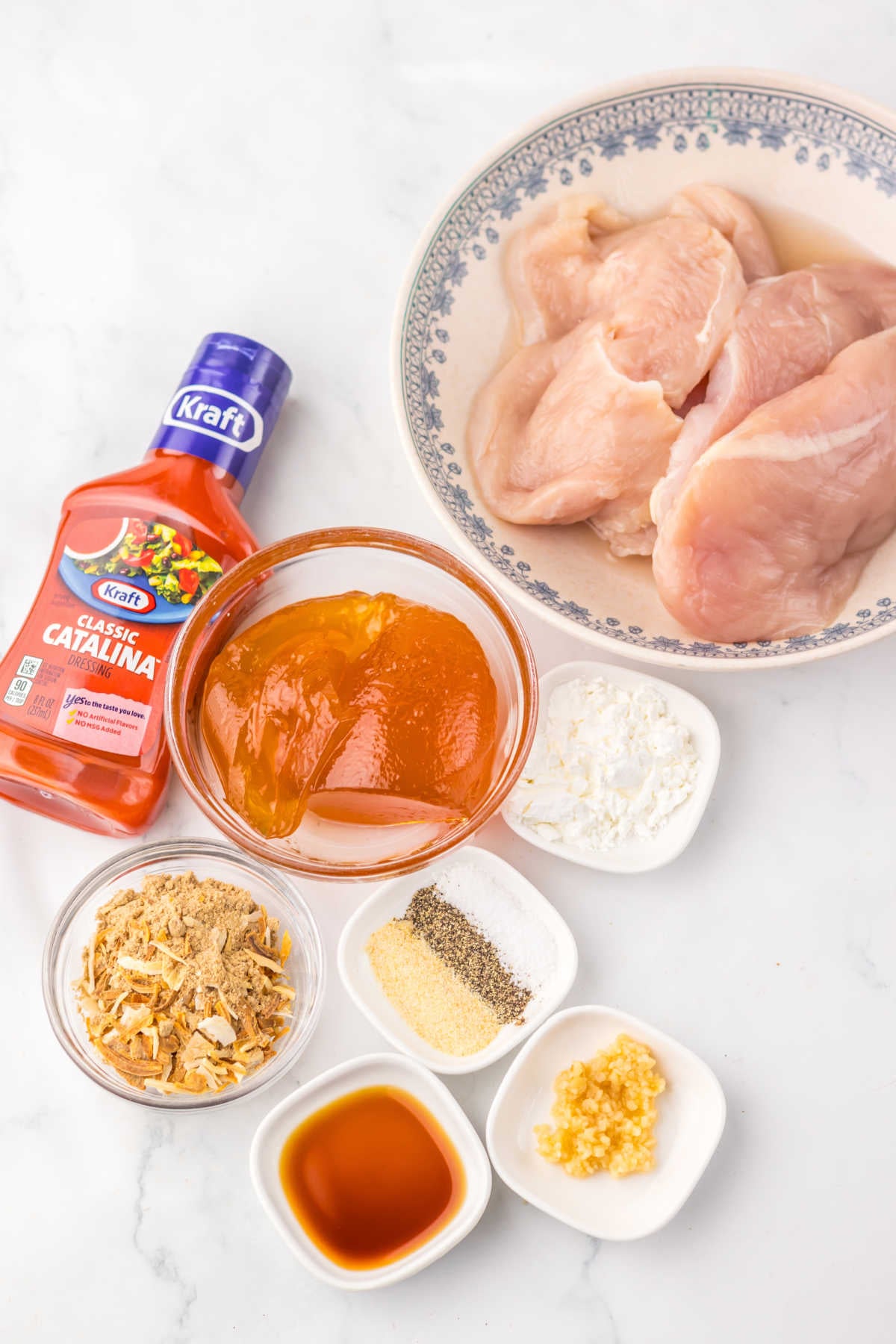Ingredients including Catalina dressing, apricot jam, onion soup mix, chicken breasts, and seasonings ready to be made into crockpot catalina chicken. 