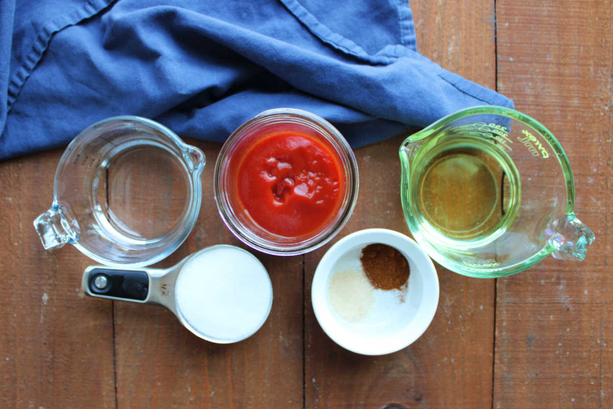 Ingredients including vinegar, ketchup, oil, sugar, onion powder, and paprika ready to be made into homemade catalina salad dressing. 