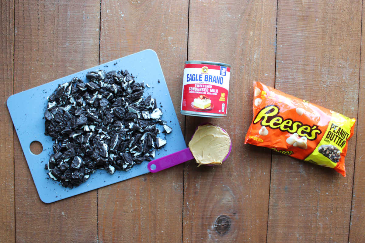 Ingredients including chopped Oreo cookies, sweetened condensed milk, creamy peanut butter, and peanut butter chips ready to be made into peanut butter Oreo fudge. 