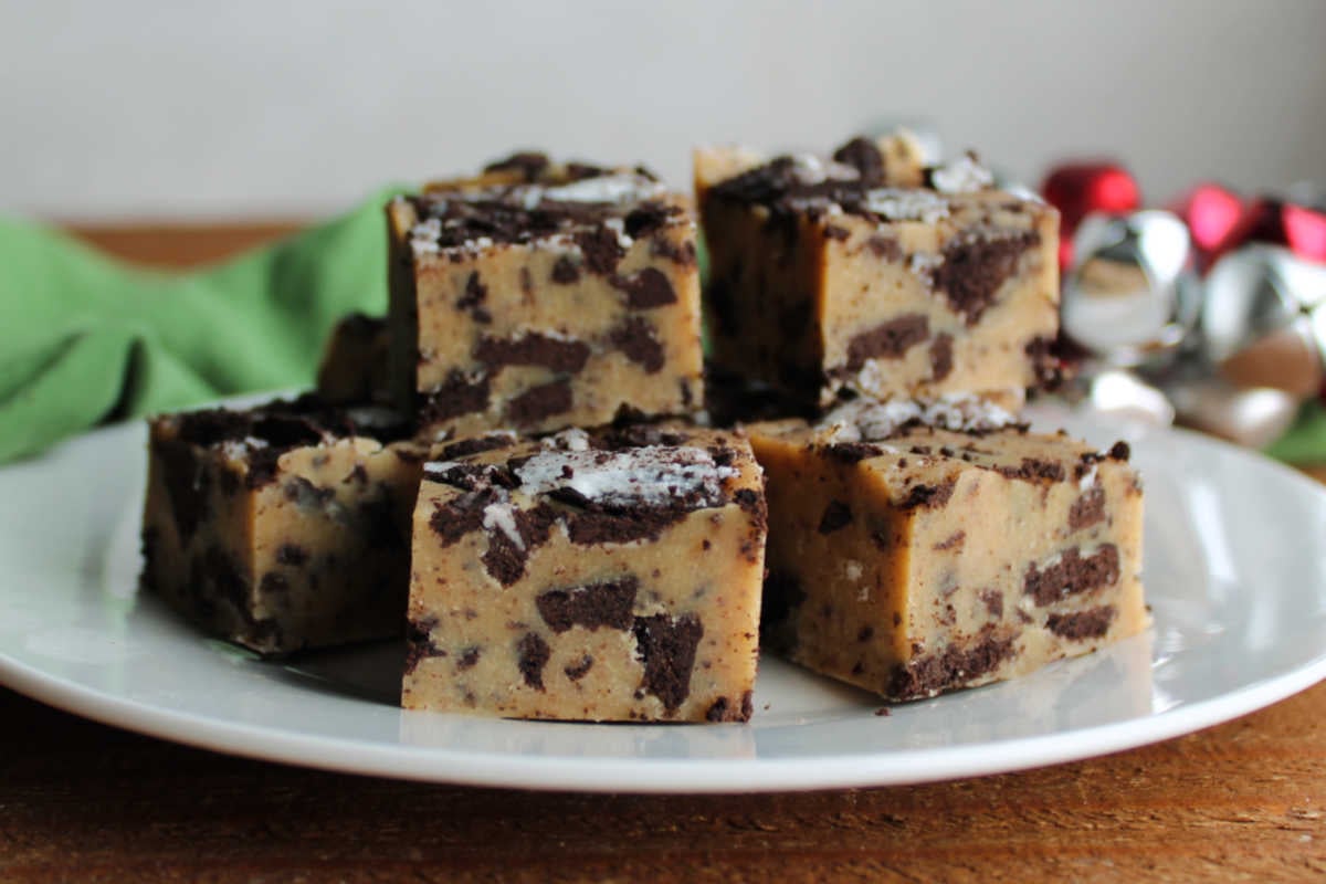 Pieces of peanut butter Oreo fudge on plate showing creamy peanut butter fudge texture with bits of cookie throughout. 
