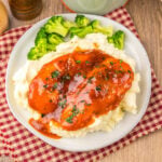 Dinner plate with slow cooked catalina chicken served over mashed potatoes with a side of broccoli.