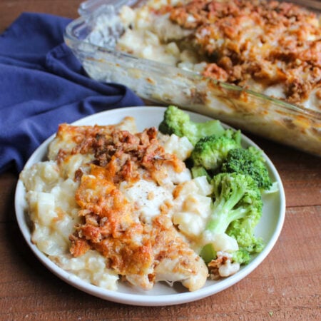 Cheesy Chicken and Potato Casserole 1 Dinner plate with helping of casserole with creamy hash brown mixture topped with pieces of chicken topped with browned cheese and french fried onions served with steamed broccoli, ready to eat..