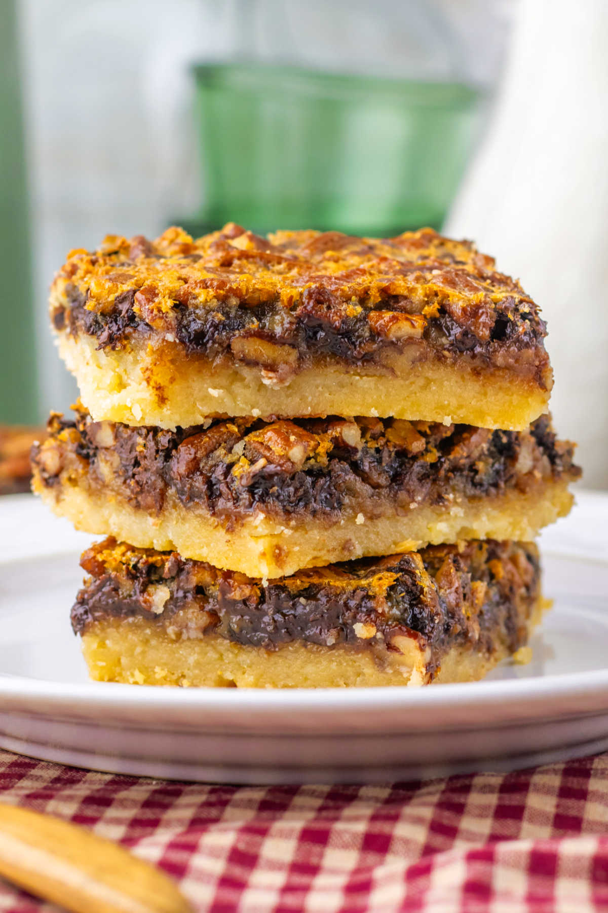Stack of chocolate pecan pie bars with shortbread crust, gooey chocolate filling, and lots of pecans on top, ready to eat. 